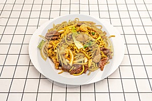 Three delights tagliatelle with beef, chicken, lettuce and onion on a white tablecloth