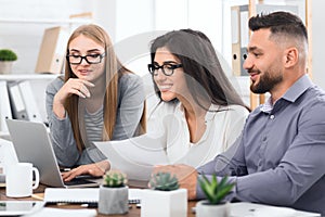 Three designers working together on laptop in office