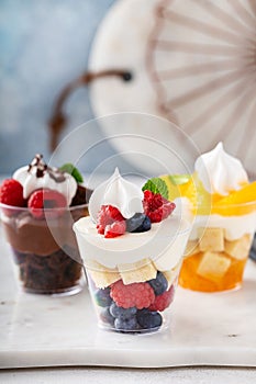 Three desserts in cups, variety of trifles with orange, chocolate and berry