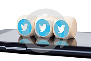 Three dice with blue Twitter bird logo icons on a modern smartphone screen. Social media engagement concept, addiction. Tweeting