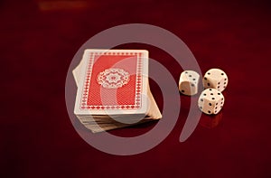 Three dice cubes and deck of cards on dark reflecting wooden background games casino fortune