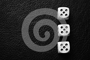 Three dice with fives on a black leather table. Bw photo. Top view