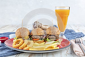 Three different burger with pickles onion rings and french fries on red plate with copy space, top view