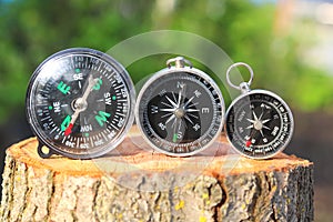 Three different classic navigational compass on stump in summer