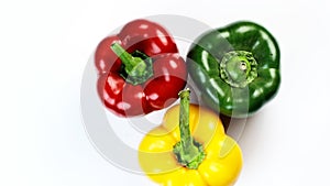 Three different colored bell peppers isolated against the white background. Red, yellow and green capsicums also known