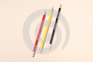 Three different colors pencils on a beige paper background with copy space for your text