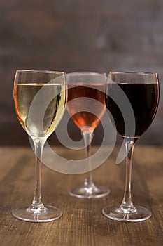 Three different glasses of wine on a wooden surface