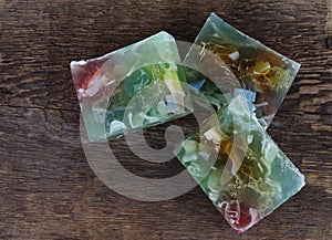 Three different handmade pieces of soap against the background of a coarse wood texture