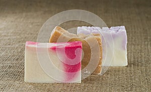 Three different handmade pieces of soap on a background of rough burlap