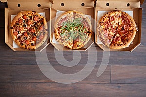 Three different kind of pizzas in delivery boxes