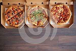 Three different kind of pizzas in delivery boxes