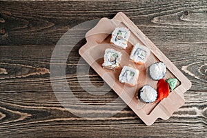 Three different kinds of Japanese rolls with wasabi and ginger on bamboo tray on beautiful wooden background