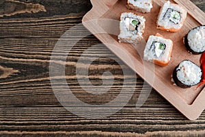 Three different kinds of Japanese rolls with wasabi and ginger on bamboo tray on beautiful wooden background