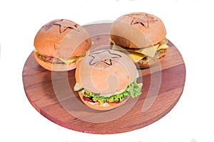 Three different large and juicy burgers on a wooden tray isolated on white background.