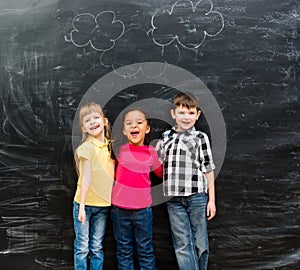 Three different laughing children with blackboard on background