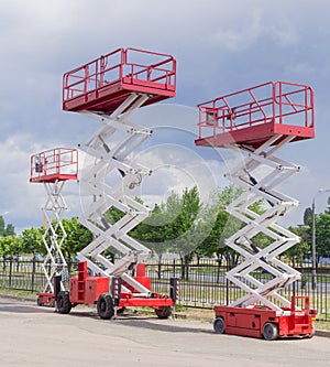 Three different scissor wheeled lifts on asphalt ground