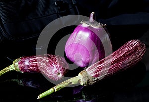 Three purple eggplants on black back ground.