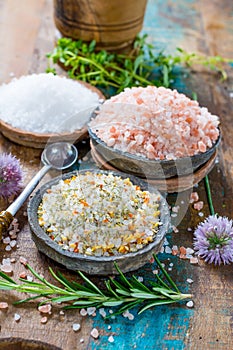 Three different types of natural salt in stone bowls on wooden s
