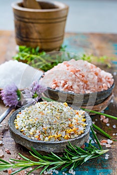 Three different types of natural salt in stone bowls on wooden s