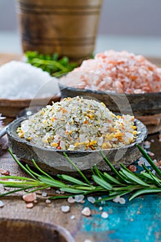 Three different types of natural salt in stone bowls on wooden s