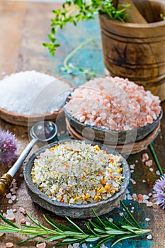 Three different types of natural salt in stone bowls on wooden s