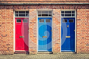 Three differently coloured front doors at the entrance of old En