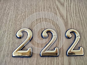 Three-dimensional brass numbers affixed to wood. Brass Numerals 222 Mounted on Wooden Surface