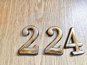 Three-dimensional brass numbers affixed to wood. Brass Numerals 224 Mounted on Wooden Surface