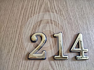 Three-dimensional brass numbers affixed to wood. Brass Numerals 214 Mounted on Wooden Surface photo