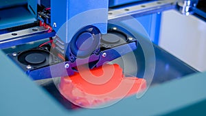 Three dimensional printing machine prints physical red 3D model - close up