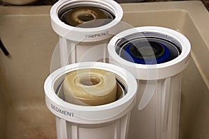 Three dirty used osmosis water filter cartridges