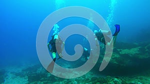 Three divers swim ahead over the sea floor