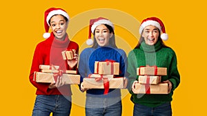 Three Diverse Girls Holding Xmas Gifts Standing, Yellow Background, Panorama