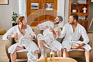 Three diverse men in bathrobes sit