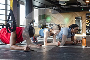 Three diverse people doing planks in gym