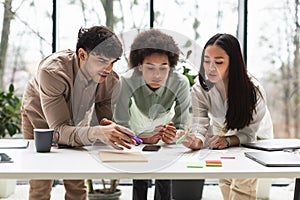 Three Diverse Young Business Professionals Brainstorming Working Together In Office