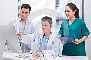 Three doctors discussing patient files on office