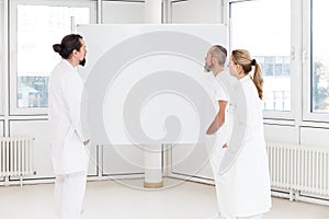 Three doctors looking to a empty whiteboard, concept medicine and healthcare