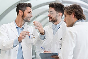 three doctors in white coats having conversation at hospital hall