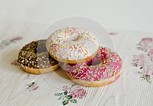 Three donuts on a background in the style of a shabby chic.