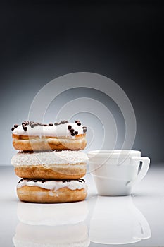 three donuts and cup of coffee on dark background