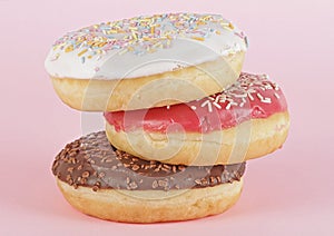 Three donuts with icing on pink background. Sweet donuts