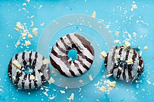 Three donuts with white chocolate chips on blue background