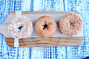 Three donuts on wooden cutting board