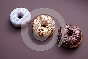 three doughnuts isolated on brown background