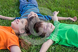 Three dreaming kids lying down on green grass