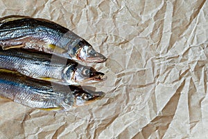 Three dried fish on parchment paper. Selective focus. Copy space
