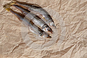 Three dried fish on parchment paper. Selective focus. Copy space