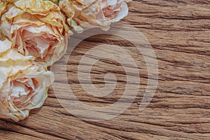 Three dried pink roses on wooden