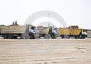 three dump trucks standing in a row at a construction site